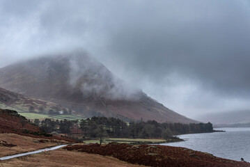 Wall Mural - Moody dramatic Winter foggy landscape image of Wast Water in English Lake District with thick fog blocking view of mountains in distance