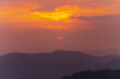 Top view of the sunset is getting disappearing in the sky. Clouds are orange yellow and pink with colorfull. There are many layers of mountains below. The idea for natural wallpaper with copy space.