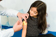 © AntonioDiaz - Adorable girl patient getting a distracting device vaccine