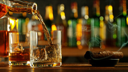 Wall Mural - Detail of pouring whiskey into glass with ice cubes.