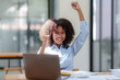 © amnaj - Businesswoman raising her hand in congratulation with document and laptop computer