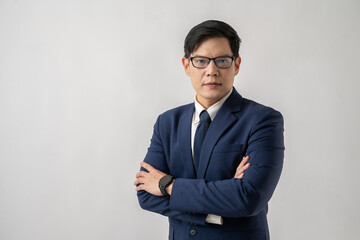 Portrait of confident Asian businessman in glasses standing with arms crossed on white background