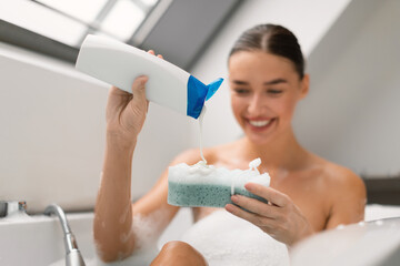 Wall Mural - Woman Taking Bath Squeezing Shower Gel On Sponge In Bathroom