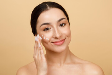 Wall Mural - Beautiful Young Indian Female Applying Moisturizing Cream On Face