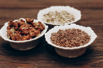 Wall Mural - A mixture of sunflower, pumpkin and flax seeds with nuts in a bowl on a wooden table.