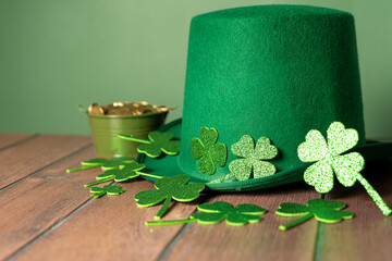 Celebrating St. Patrick's Day with a touch of luck: green hat, shamrocks and coins on a wooden table. High quality photo