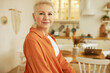 © Anatoliy Karlyuk - Indoor portrait of pretty adorable stylish mature female posing with smiling face against kitchen background, enjoying leisure time. Senior house owner standing in living room of studio apartment