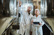 Two workers wearing lab coats inspecting equipment at food factory