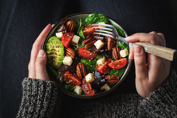 Healthy homemade salad with tomatoes, cheese cubes, pecans, avocado, spinach and arugula.