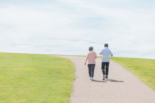 公園でウォーキング・有酸素運動する高齢者夫婦の後ろ姿（シニア・男女）