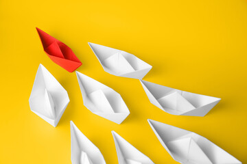 Poster - Group of paper boats following red one on yellow background. Leadership concept