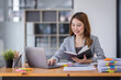 © David - Young asian business woman manager accounting analyst checking bills, analyzing sales statistics management, taxes financial data documents or marketing report papers working in office using laptop.