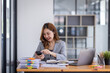© David - Smiling young Asian business woman executive looking at smartphone using cellphone mobile cell tech, happy ethnic professional female worker working in office typing on cellphone sitting at desk.