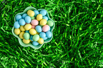 Wall Mural - Bowl of candy coated easter eggs in a nest of easter grass, as a holiday background
