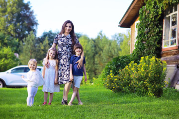 Wall Mural - Young large family on a summer morning walk. Beautiful mother with children is playing in the park.