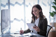 © Tj - Sharing good business news. Attractive young businesswoman talking on the mobile phone and smiling while sitting at her working place in office and looking at laptop PC.
