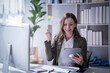 © Tj - Sharing good business news. Attractive young businesswoman talking on the mobile phone and smiling while sitting at her working place in office and looking at laptop PC.