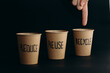© Westend61 - Man's hand pointing at reusable cup with recycle text written on it against black background