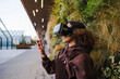 © Westend61 - Young woman with VR goggles pointing on footpath