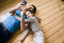 Daughter Lying By Father Using Smart Phone At Home