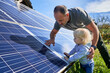 Man showing little child the solar panels during sunny day. Father presenting to his kid modern energy resource. Little steps to alternative energy.