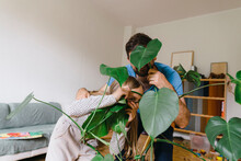 Father And Daughter Hiding Behind Plants At Home