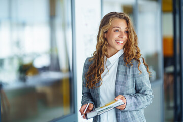 Young  business woman standing against office interior background.  People, business, freelance, work concept 