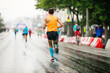 © sports photos - back runner athlete run in rain on road city marathon