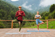 © Drobot Dean - Athletic couple doing exercises and holding palms together during yoga practice in mountains