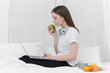 © itchaznong - Portrait of Good Healthy woman eating green apple and resting in bed at bedroom. Lifestyle at home concept.