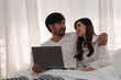© itchaznong - Beautiful asian couple in love and smiling sitting on bed. Romantic moment, relationships, family concept.