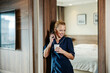 © Dusan Petkovic - A chambermaid is taking a break while talking on the phone and holding cup of coffee in a hotel room.