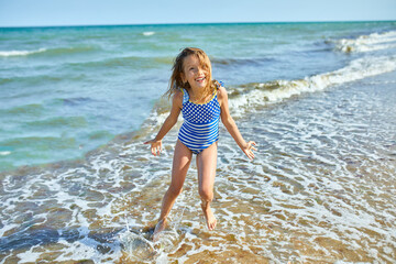 Happy, joyful little girl run on the beach