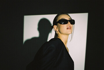 Wall Mural - Film photography, noise and selective focus.Portrait of a fashion model with sunglasses posing in the studio