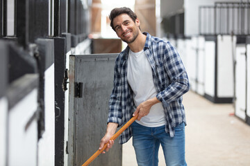 male worker cleaning floor at stabling