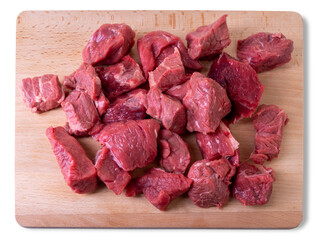 Wall Mural - Raw beef diced for stew on wooden cutting board in top view