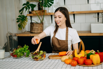 beautiful adult woman while making salad at open kitchen. healthy food concept..