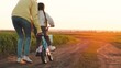 © Валерий Зотьев - mother teaches child ride two-wheeled bicycle sunset. fun weekend by bike. child's dream kid. child drive bicycle. mom rides girl child daughter bikerays sunset. happy family concept. teamwork