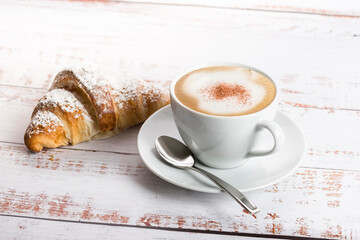 Wall Mural - Breakfast with cappuccino and croissant on wooden table.