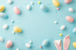 Easter composition concept. Top view photo of yellow white blue pink eggs easter bunny ears and sprinkles on isolated pastel blue background with copyspace in the middle