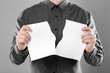 Man ripping sheet of paper on grey background, closeup. Mockup for design