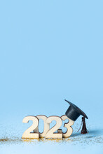 Class Of 2023 Concept. Wooden Number 2023 With Graduated Cap On Colored Background