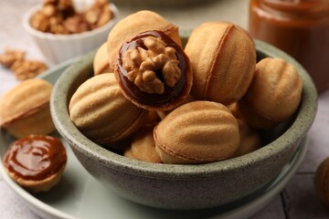 Delicious nut shaped cookies with boiled condensed milk in bowl, closeup