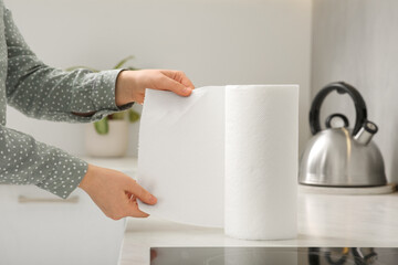 Wall Mural - Woman tearing paper towels in kitchen, closeup