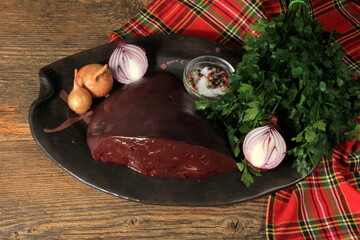 Wall Mural - raw cow's liver on a plate with spices, herbs, onions and garlic