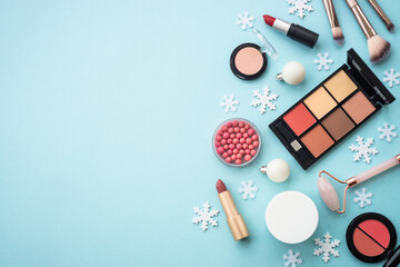 Wall Mural - Make up products and christmas decorations on blue background. Holiday shopping. Flat lay image with copy space.