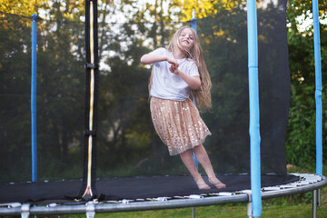 Little child girl jumping on the trampoline in the back yard