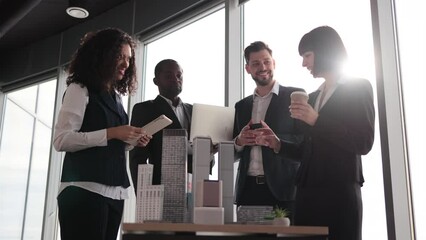 Wall Mural - Diverse group of multiracial business people in the conference room with panoramic city view cooperating standing near table with 3d skyscraper building maquette. Teamwork concept.