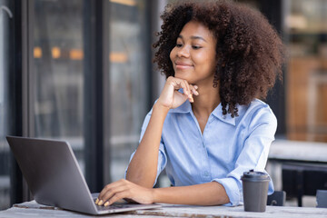 Young happy professional business woman worker employee sitting at desk working on laptop in corporate outside. Smiling female student using computer technology learning online, doing web research.
