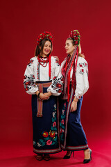 Wall Mural - Ukrainian women in traditional ethnic clothing and floral red wreath on viva magenta studio background. National embroidered dress call vyshyvanka. Pray for Ukraine